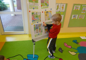 Chłopiec przywiesza na tablicy ilustracje prezentującą jedno z praw dziecka.